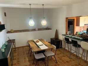 A dining area with a wooden table, chairs, and hanging pendant lights. - Sleeps4-familyfriendly-balcony (Lagoa)