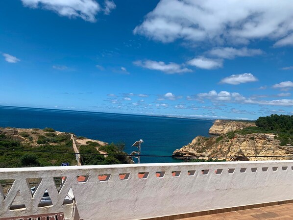 A coastal view with a clear sky, rocky terrain, and a distant shoreline. - Sleeps4-familyfriendly-balcony (Lagoa)