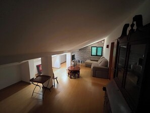 A spacious loft with a high ceiling, a dining area with a round table, a sofa, and a stone wall with a window. - Sleeps4-familyfriendly-balcony (Lagoa)
