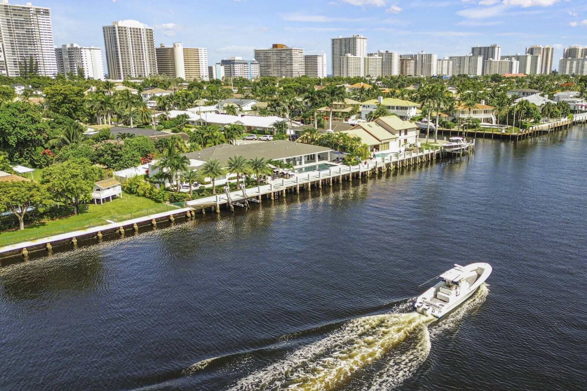 A waterfront property with a dock, a boat, and a city skyline in the background.