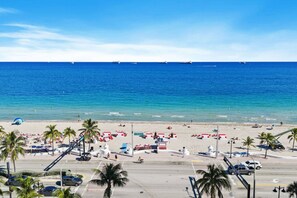 Una playa con palmeras, sombrillas y un camino que lleva a la playa.