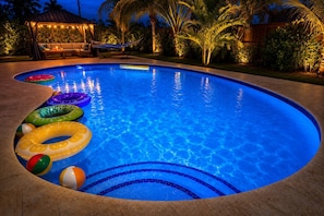 Ein Swimmingpool mit Schwimmreifen und eine Liegefläche mit überdachter Sitzgelegenheit.