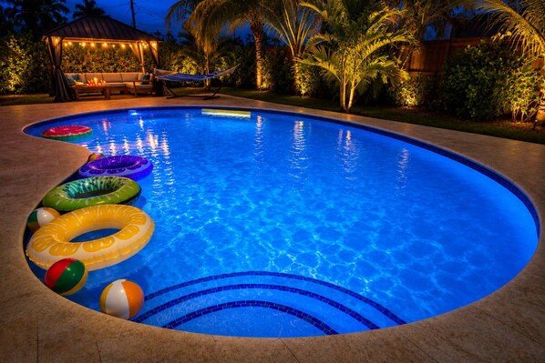 En pool med uppblåsbara badringar och ett område med bekväma sittplatser under ett tak.