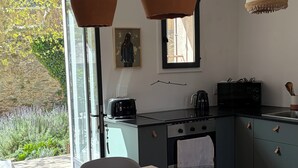 Una cuina moderna amb una taula de fusta, un torrador negre i un bullidor.