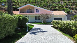 Ein modernes Haus mit gepflasterter Auffahrt, umgeben von üppigem Grün und einem gepflegten Garten.