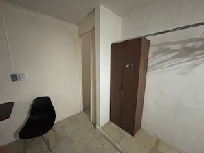 A room with a wardrobe, a chair, and a door leading to another room. - Casa Vega (Mérida)