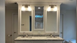 Un baño con tocador doble, dos lavamanos y un espejo grande con iluminación.