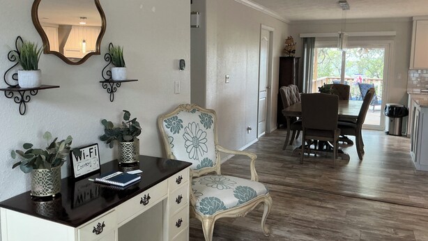 Un área de comedor con una mesa y sillas, un espejo decorativo y plantas en macetas en la pared.