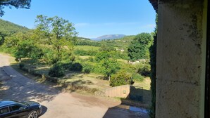 A rural landscape with a dirt road, trees, and a car parked on the side. - Gite 2 Moulin SAINT ETIENNE (Bédarieux)