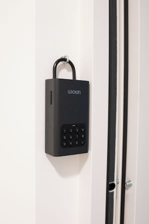 A black electronic keypad lock mounted on a white door. - Waterfront City Buda Hills Views&Free parking (budapest)