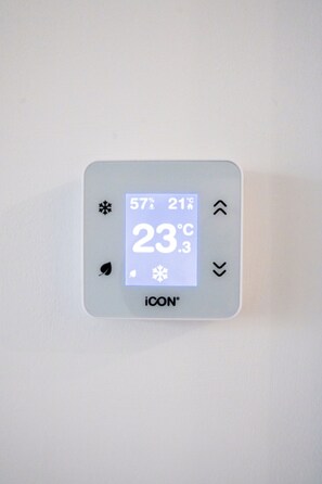 A thermostat with a digital display showing 23°C, weather symbols, and the brand ICON. - Waterfront City Buda Hills Views&Free parking (budapest)