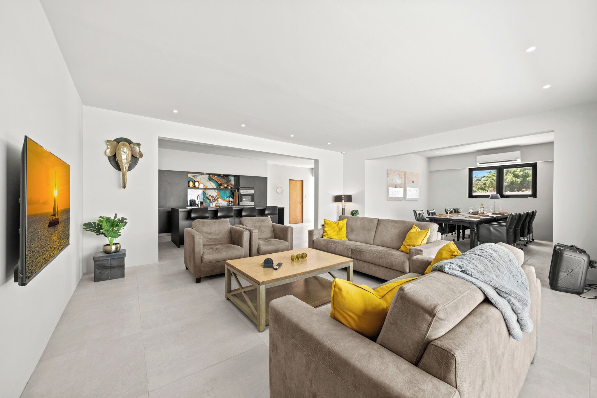 A modern living room with a sofa, coffee table, and a dining area with chairs.