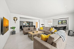 Un salon moderne avec un canapé, une table basse et un coin repas avec des chaises.