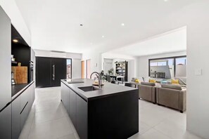 Une cuisine moderne dotée d’un îlot central, d’un coin repas avec un canapé et d’une vue sur l’extérieur.