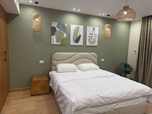 A modern bedroom with a bed, wall art, and pendant lights.