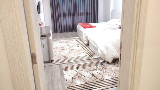 A hotel room with a bed, a desk, a chair, a window with curtains, and a door. - Diarna Downtown Residency (Marsa Matrouh Governorate)