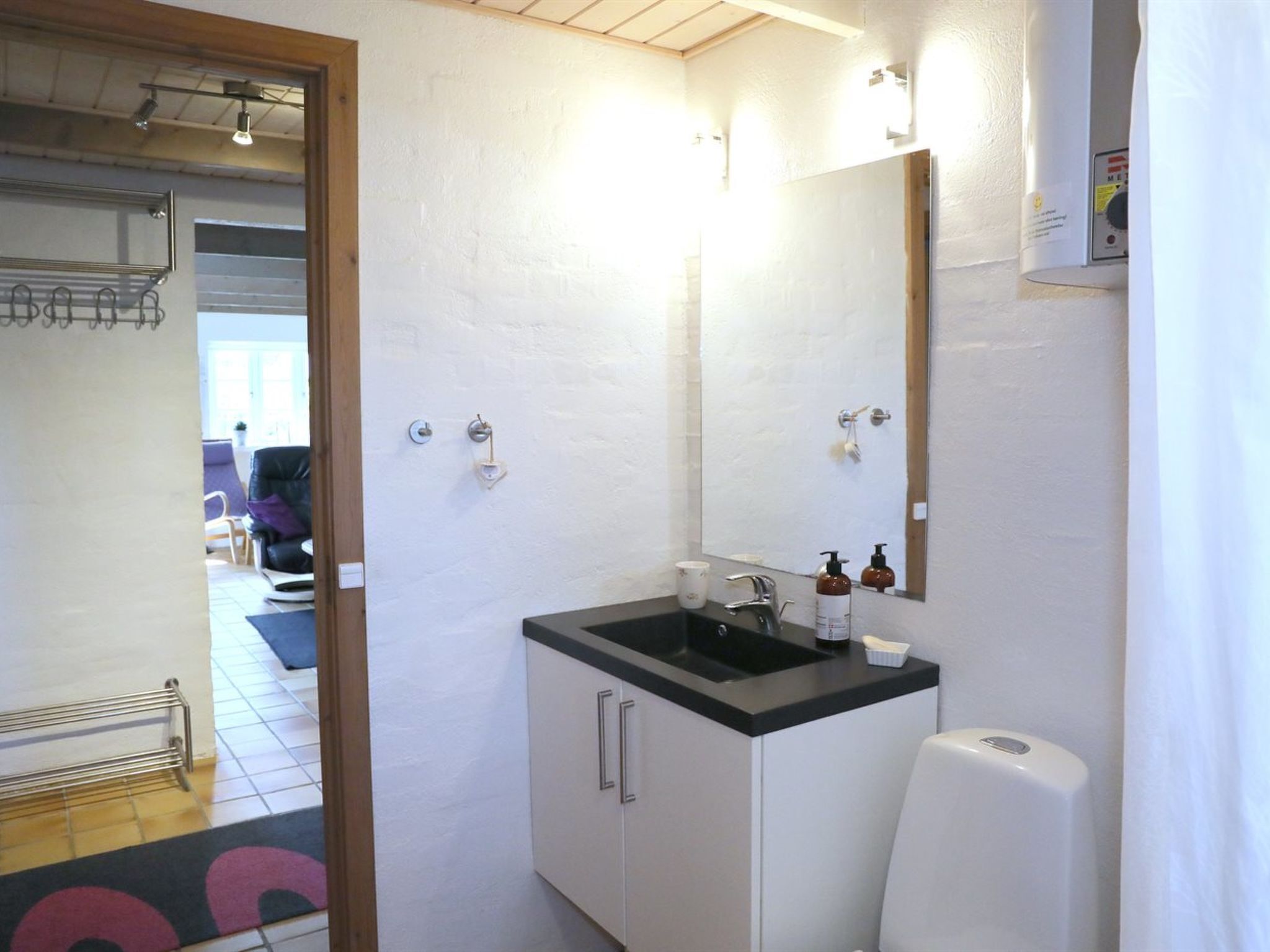 A bathroom with a sink, mirror, and hand soap dispenser.