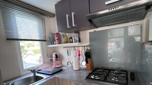 Une cuisine de taille réduite, équipée d’un évier, d’une cuisinière et de placards.