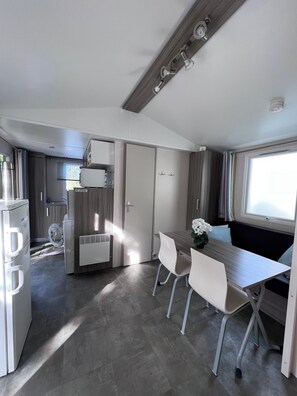 A compact kitchen with a refrigerator, stove, and a small window. - Mobile home near beach Le Pradet (Var, 83) (Le Pradet)