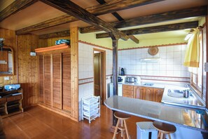 Une cuisine avec des meubles de rangement en bois, un plan de travail, des tabourets et un évier.