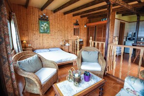 Un intérieur en bois avec deux lits, des meubles en osier, un coin repas et une cuisine.