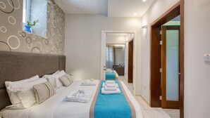 Ein Hotelzimmer mit einem großen Bett, einem Nachttisch, einem Spiegel und einem durch eine offene Tür einsehbaren Badezimmer.
