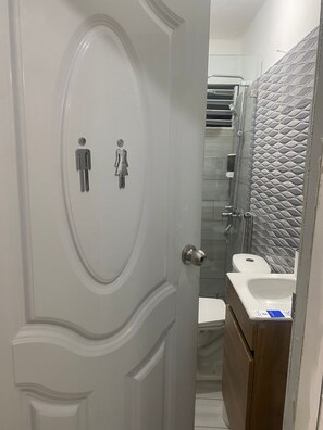 A bathroom with a white door, a sink, and a toilet.