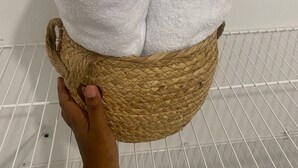 Een hand die een gevlochten mand vasthoudt, met daarin opgerolde witte handdoeken.