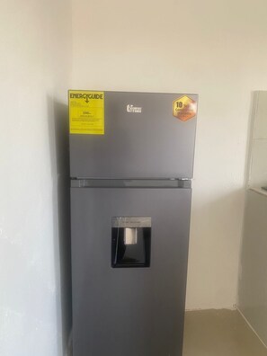 A compact refrigerator with a water dispenser, ENERGY GUIDE label, and a 10-year compressor warranty sticker.