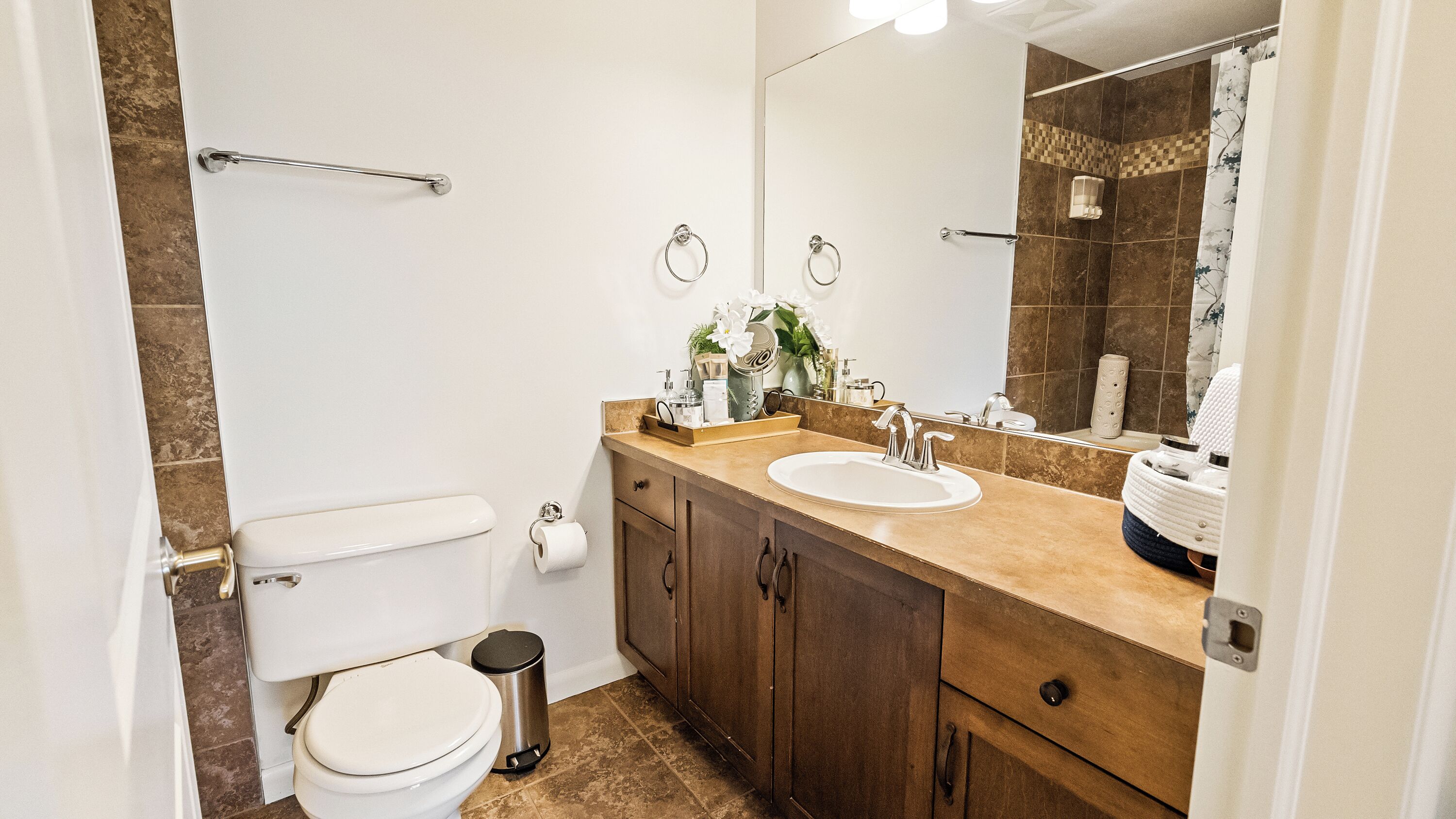 A bathroom with a toilet, sink, vanity, and a shower area.