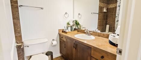 A bathroom with a toilet, sink, vanity, and a shower area.