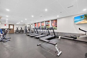 A gym with treadmills, weight machines, and a wall-mounted TV. - Bright 3 Bd at Playa 548. Pool & Beach  (Kelowna)