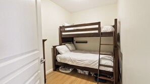 A bunk bed with a ladder, a bedside table, and a small storage box under the bed. - Bright 3 Bd at Playa 548. Pool & Beach  (Kelowna)