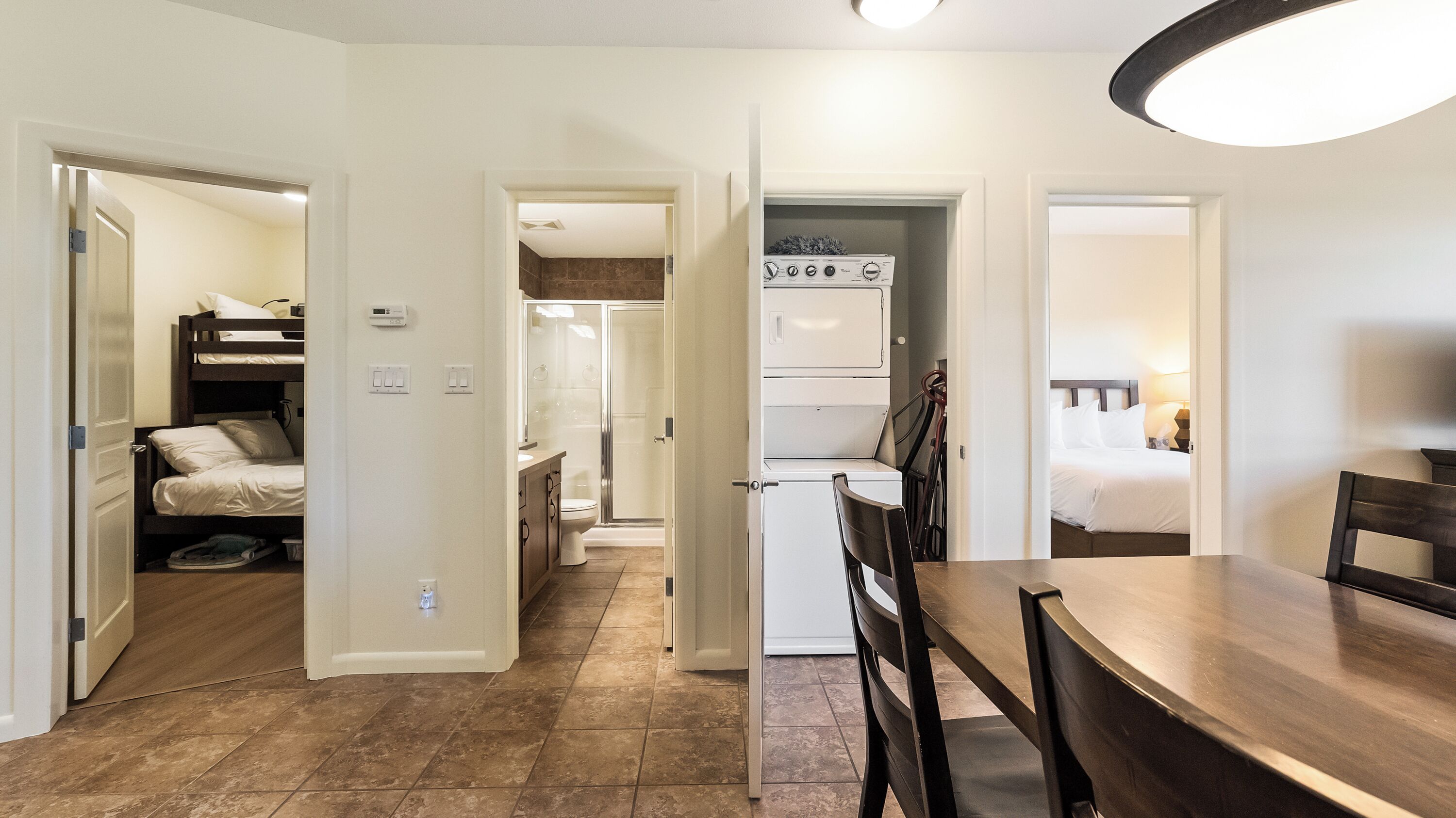 A hotel room with a kitchenette, a separate bathroom, a dining area with a table and chairs, and a bed.
