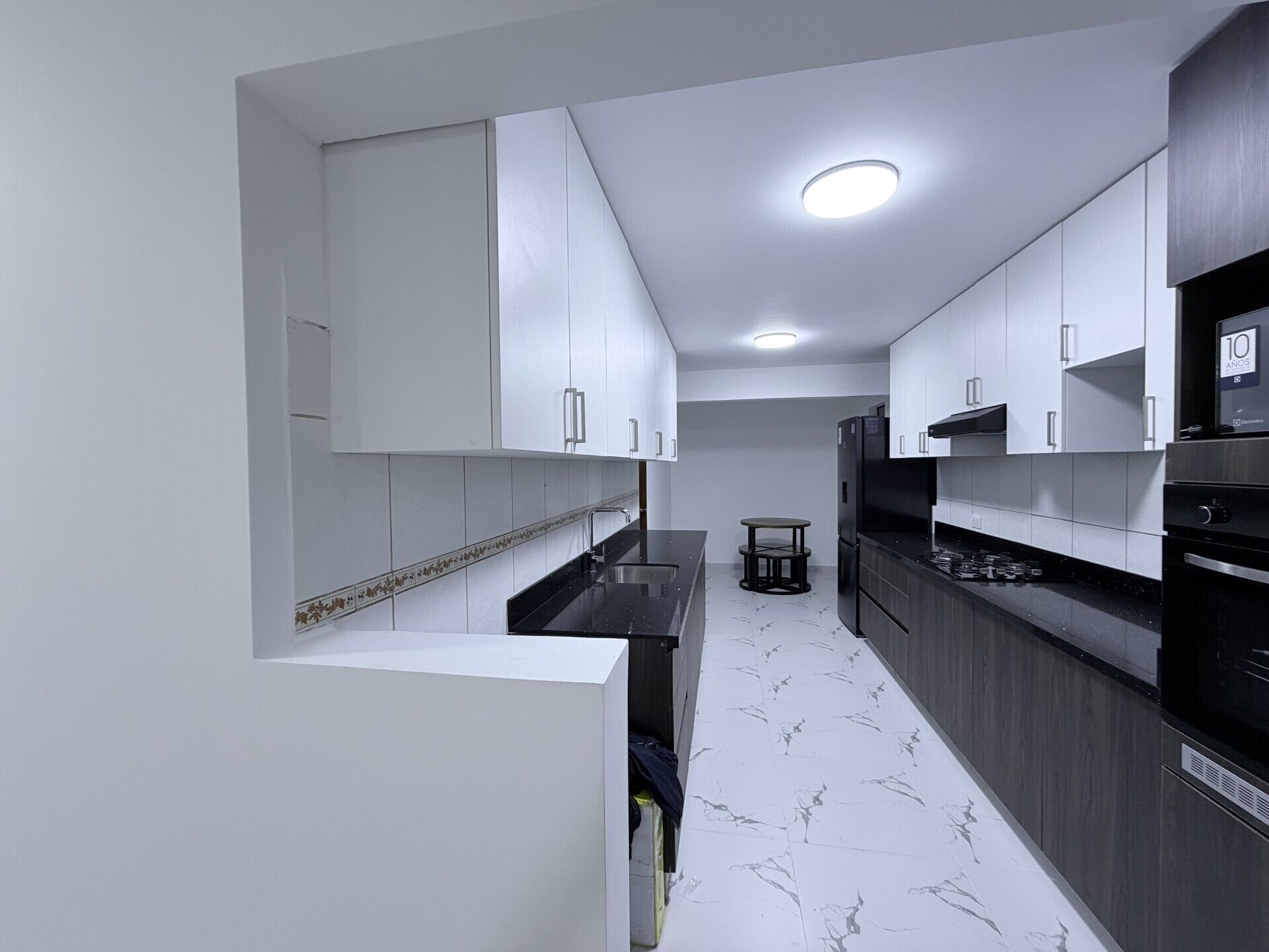Una cocina moderna con armarios blancos, encimera negra y salpicadero de mármol.