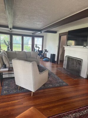 Ein Wohnzimmer mit einem Ecksofa, einem Kamin und einem großen Fenster.