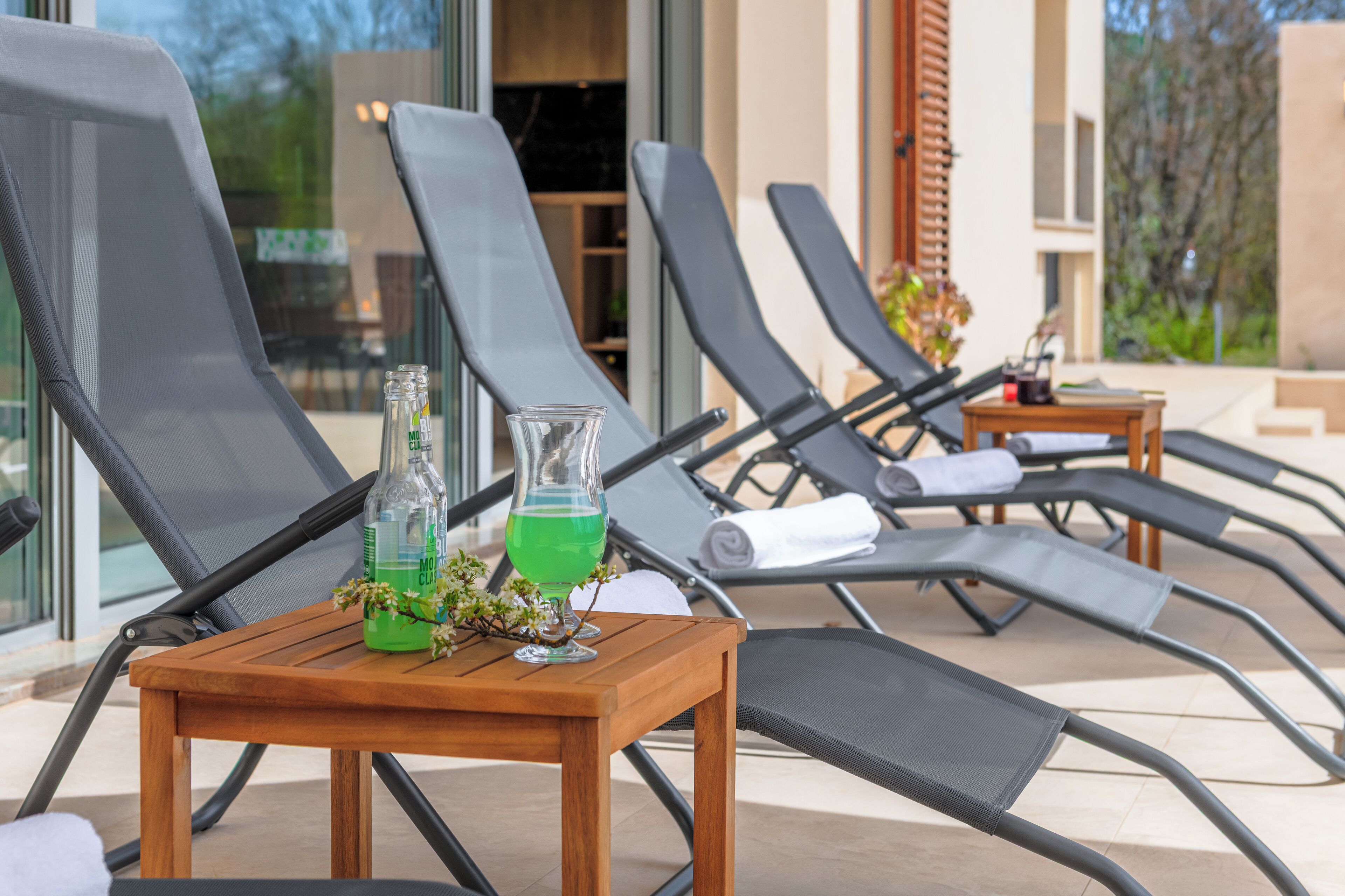 Een rij comfortabele stoelen en een houten tafel met een fles en een glas erop.