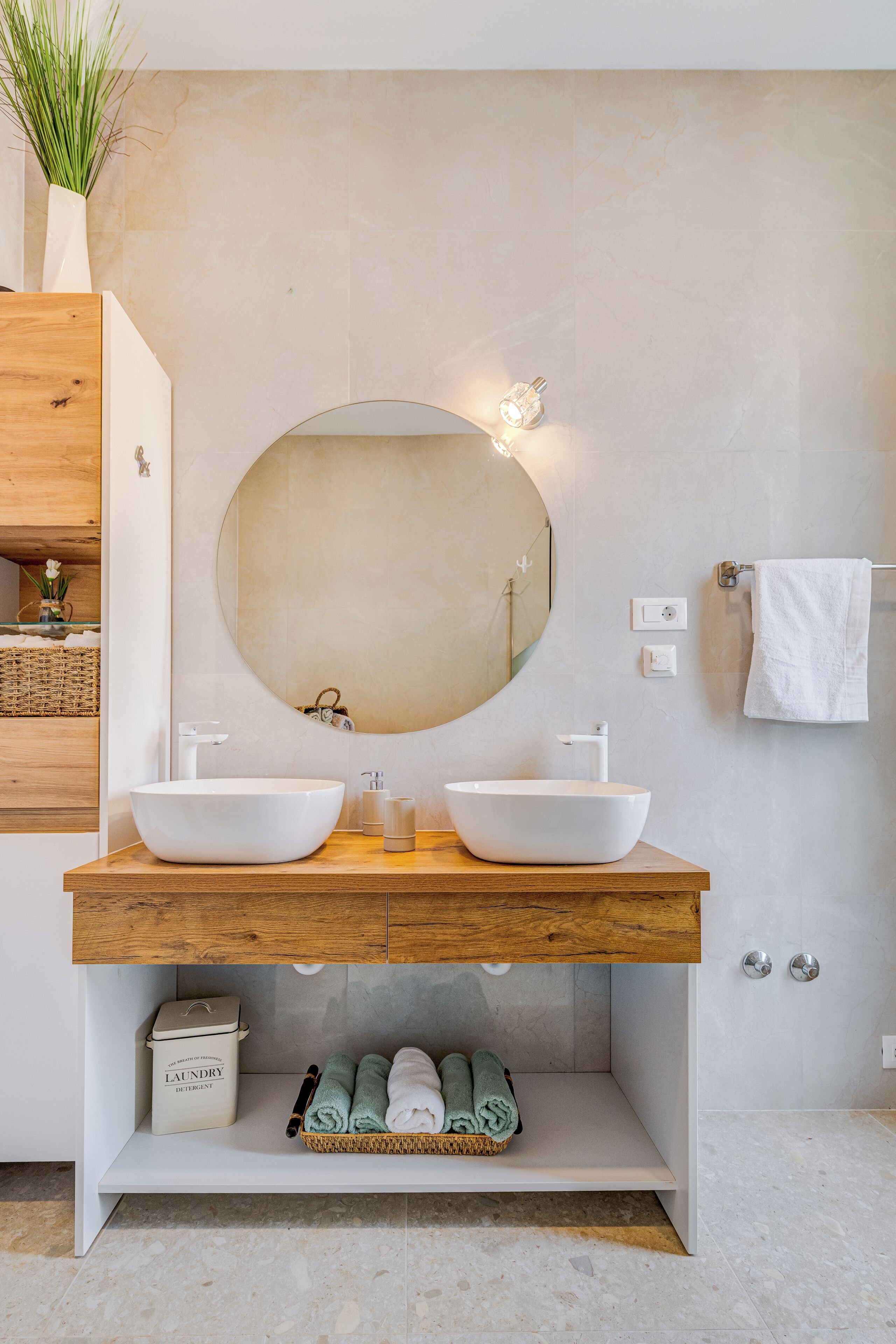 A modern bathroom with two sinks, a large mirror, and a wooden vanity.