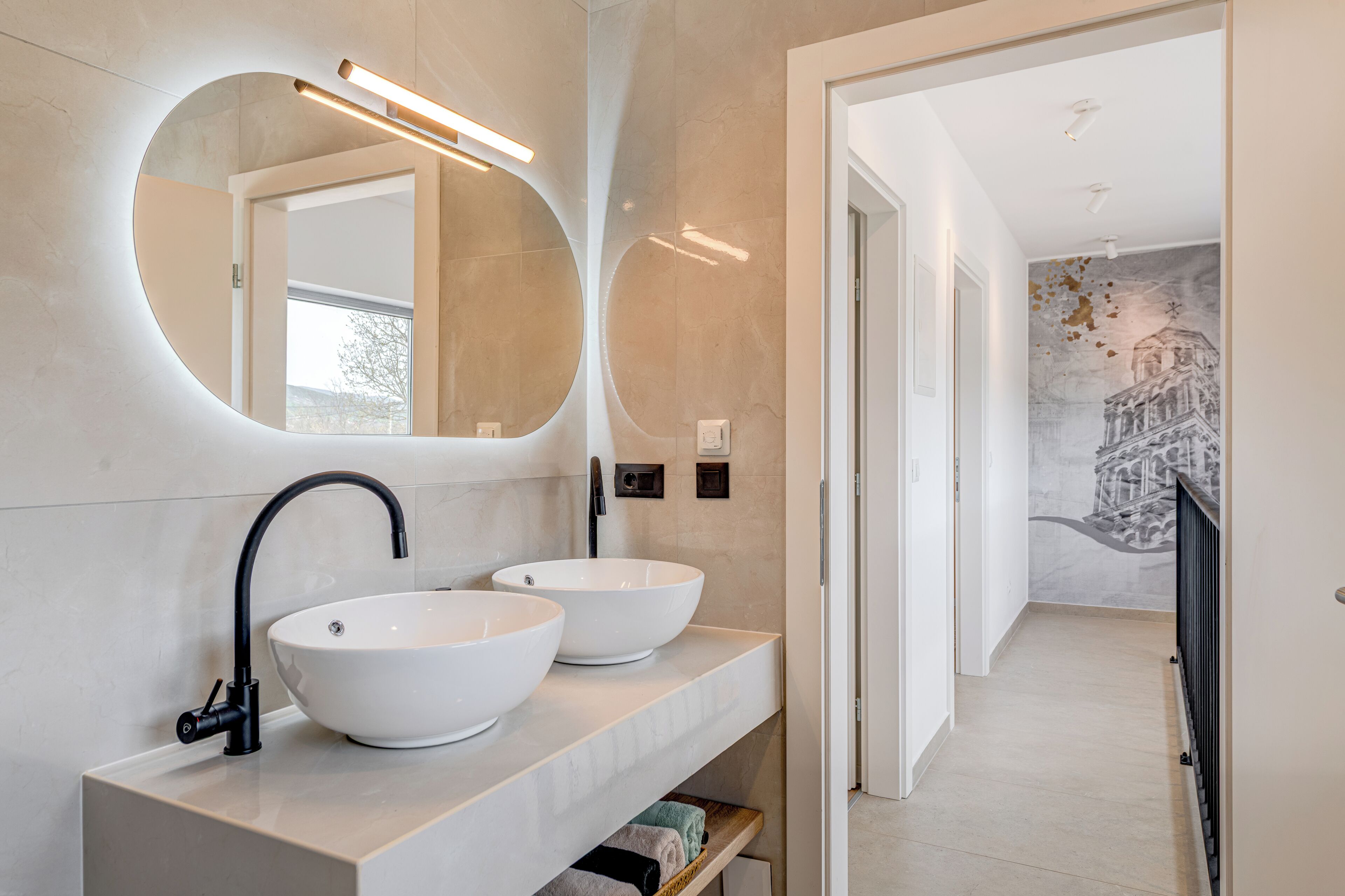 A modern bathroom with two white vessel sinks, a large mirror, and a light fixture.