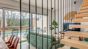 A modern interior with a staircase, a green sofa, and a view of the outdoors.