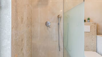 A modern bathroom with a glass-enclosed shower, a white toilet, and a marble floor.