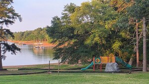 Um parque com um parquinho e um lago.