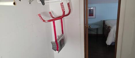 Ein Zimmer mit einem Bett, einem kleinen Tisch und einem an der Wand befestigten Ablagefach mit Gegenständen.
