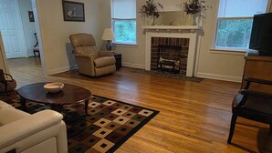 Uma sala de estar com lareira, um sofá, uma poltrona e uma mesa de centro.
