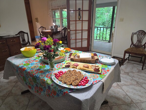 Una mesa de comedor con mantel floreado, diferentes platos y un jarrón de flores.