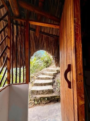 Una escala de fusta que porta a una zona exterior amb una estructura de teulat de palla.