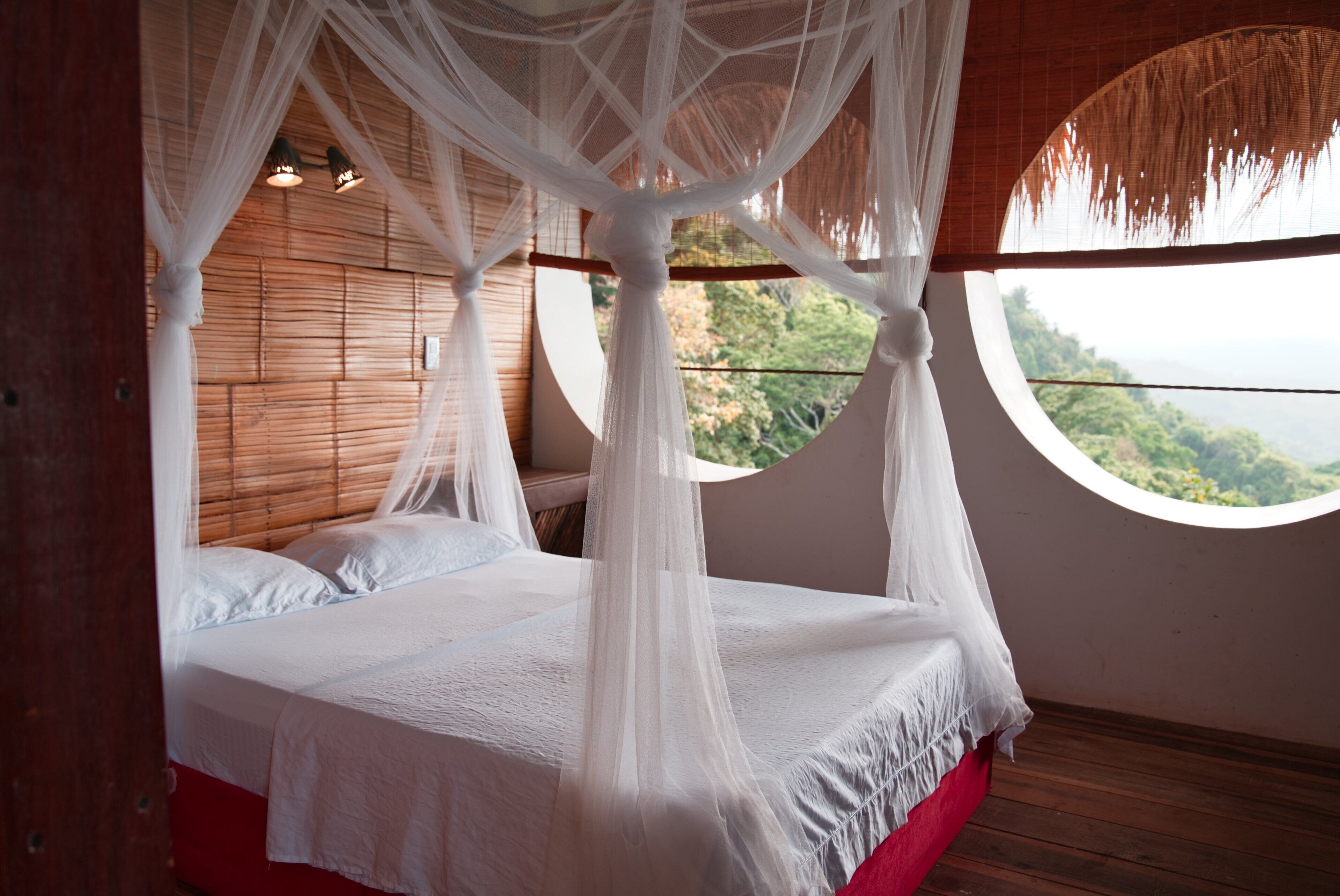 Un dormitorio con cama con dosel, paredes de madera y vistas al verdor.