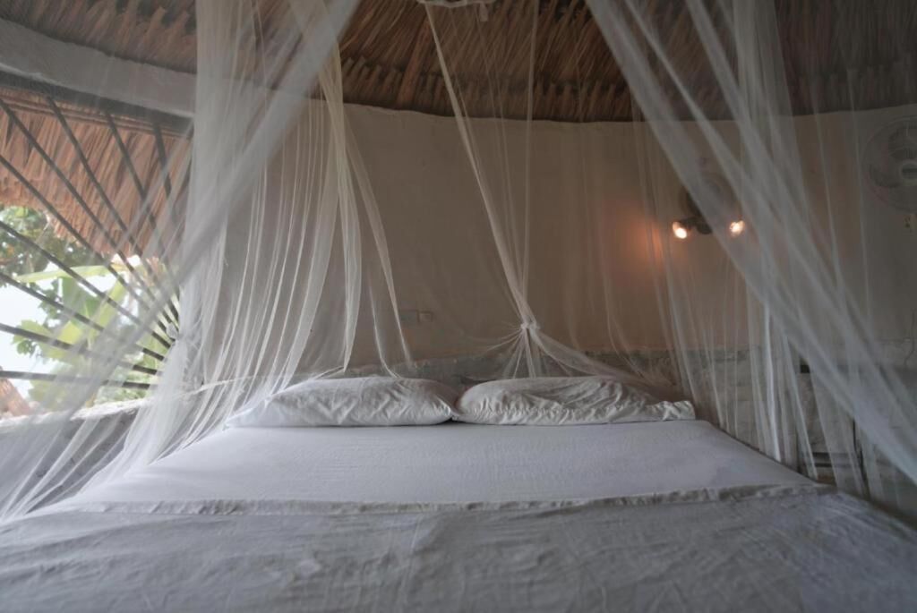 A bed with white linens and a canopy.