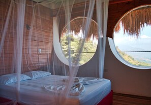 Un dormitorio con cama, ventana y vista al exterior.