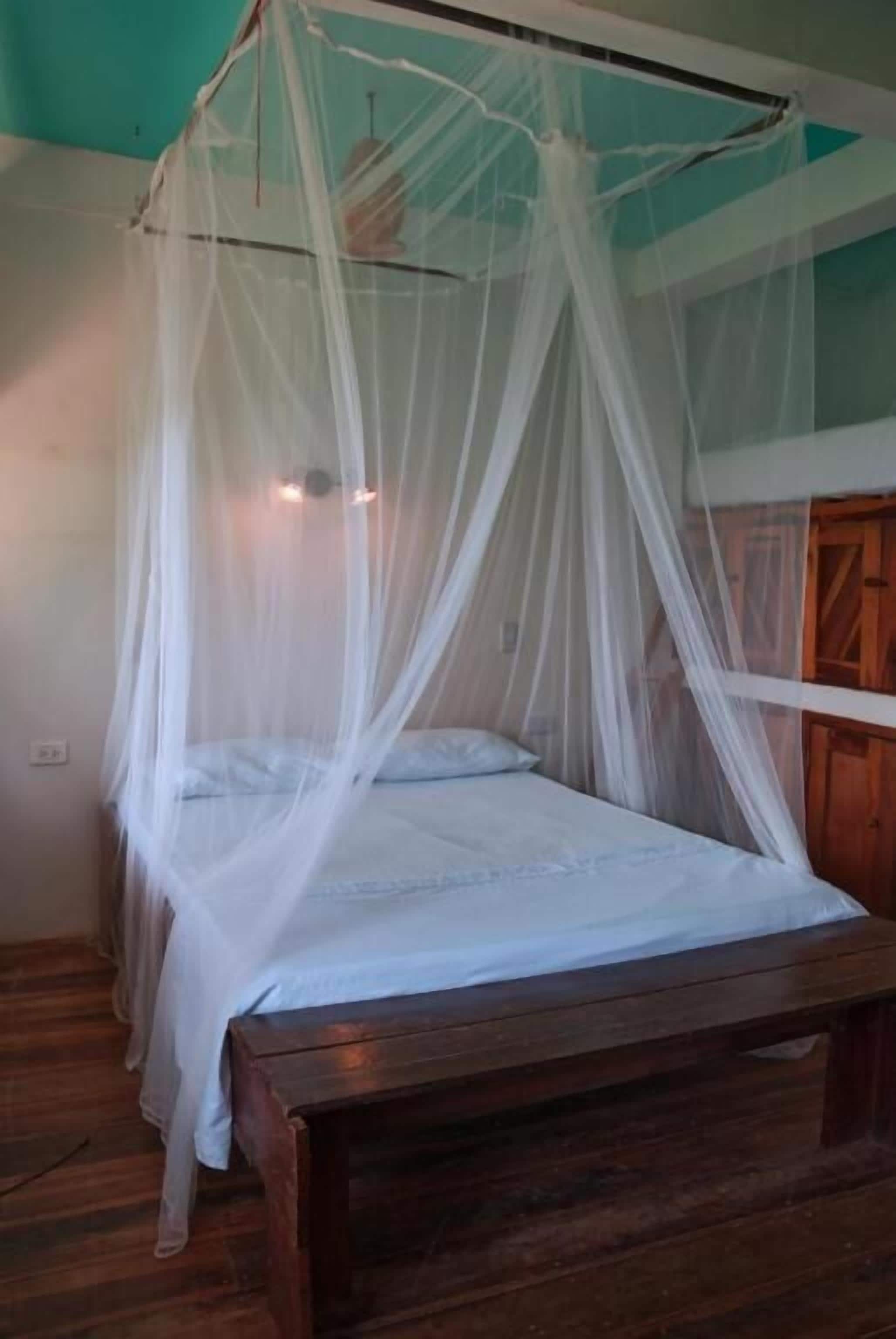 A bed with a wooden frame and a white canopy.